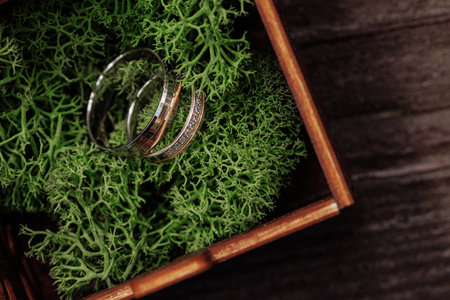 Gold wedding rings on green moss in wooden boxの写真素材