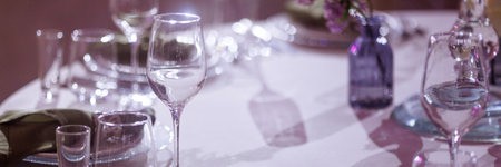 Elegant table setting in restaurant with white tablecloth and purple flowersの写真素材