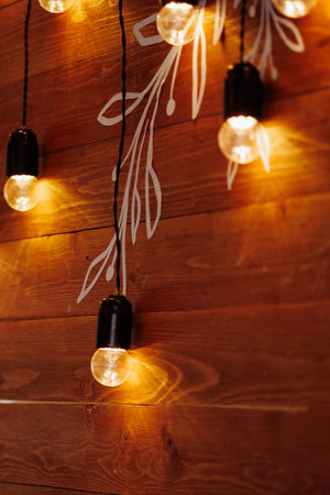 Garland of warm lamps on the background of a wooden wall.の写真素材