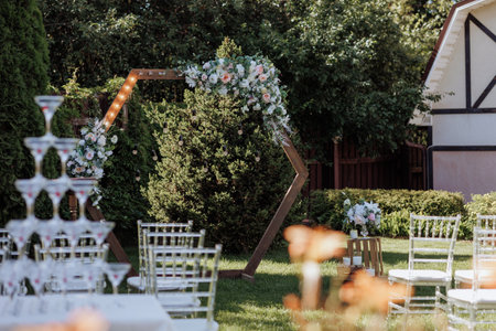 Outdoor wedding venue with floral arch and white chairsの写真素材
