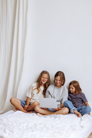 Three teenage girls are siting on the bed with a laptop.の写真素材