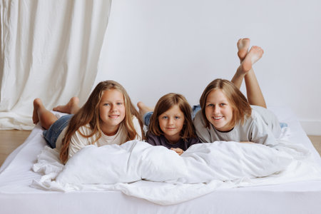 Sisters lying on a bed in their home smmiling for the camera.の写真素材
