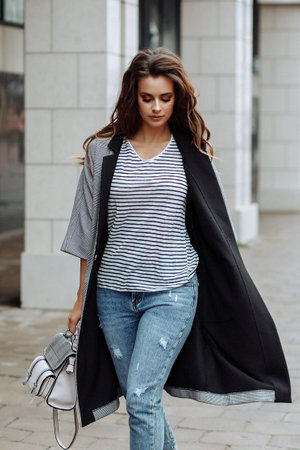 Stylish woman walking along the city sidewalkの写真素材