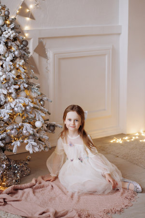 Beautiful little girl near the Christmas tree in a beautiful airy dressの写真素材