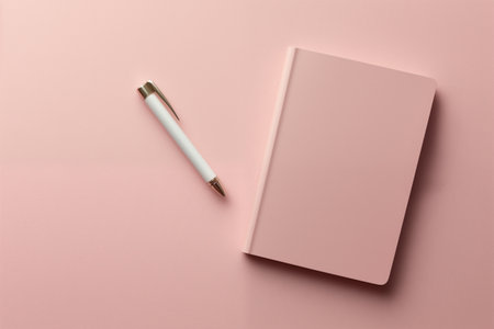 Pink notebook with silver pen, soft shadows.の素材