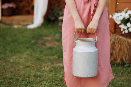 Caucasian woman in pink dress holding milk canの写真素材
