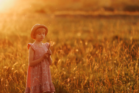 A young girl is sitting in a field of flowers, holding a bouquet of daisiesの写真素材
