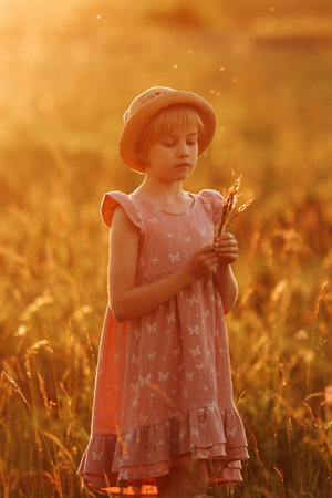 A young girl is sitting in a field of flowers, holding a bouquet of daisiesの写真素材