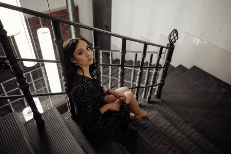 A woman in a black dress sits on a staircaseの写真素材
