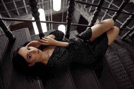 A woman in a black dress is laying on a staircase