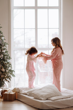 A woman and a child are playing in a room with a Christmas treeの写真素材