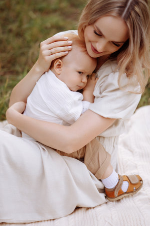 A woman is sitting on the grass with a baby in her armsの写真素材