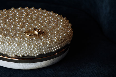 Two gold wedding rings are placed on a bed of pearlsの写真素材