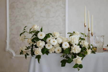 A table with a white tablecloth and a vase of white flowersの写真素材