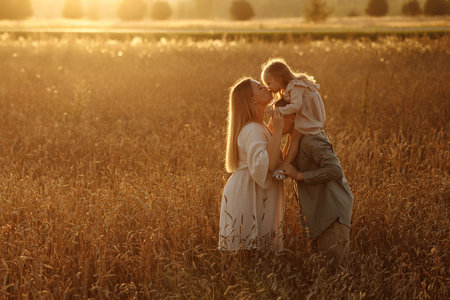 A family of four is walking through a field of tall grassの写真素材