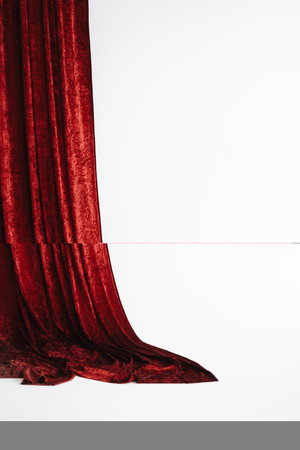 A red curtain hangs in front of a white background with copy spaceの写真素材