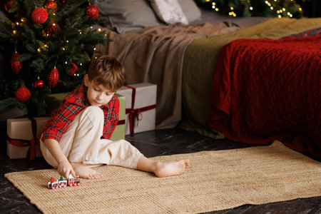 Happy boy is playing with a magic toy train at the Christmas tree.の写真素材