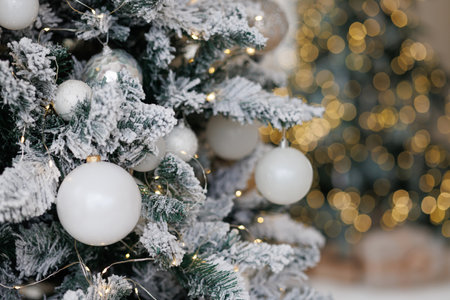 Close-up of a Christmas tree against a background of blurry garland lights.の写真素材