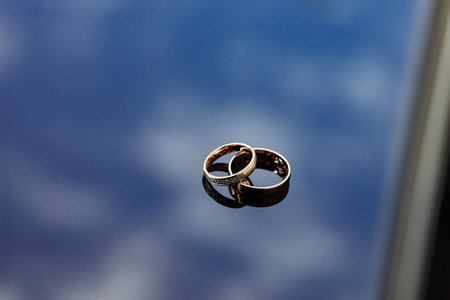 Two gold wedding rings are on a blue surfaceの写真素材