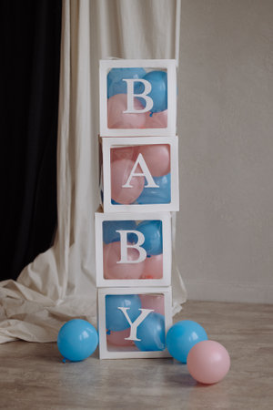 Decorations for a gender party in the form of transparent boxes with pink and blue balloons.