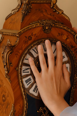 Womans Hand Stopping Time on an Antique Clockの写真素材
