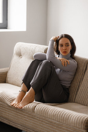 A woman is sitting on a couch with her legs crossed