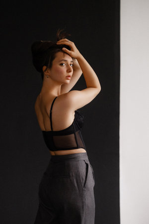 Elegant young woman in a black corset top and gray trousersの写真素材