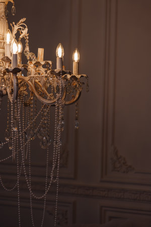 Vintage chandelier with pearls and lit bulbs in classic room with dark wall and copy spaceの写真素材