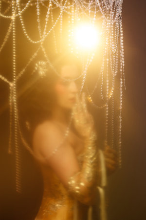 Retro-style performer in vintage costume posing on dark stage under chandelier