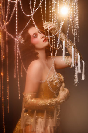 Circus-inspired retro burlesque dancer posing in golden corset with theatrical decorの写真素材