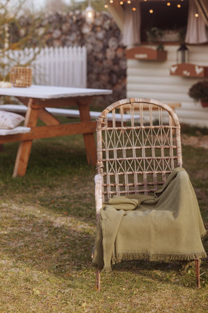 Cozy outdoor courtyard with wicker chair and green blanket.の写真素材