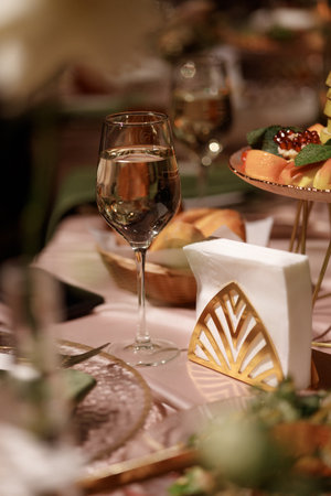 Wedding banquet table with flowers, food and candles in decorated hall with dark background