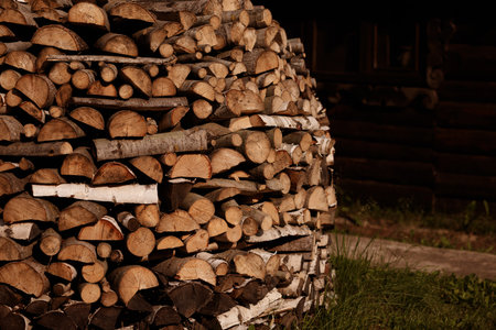 Stack of firewood near wooden house in warm sunlight with copy spaceの写真素材