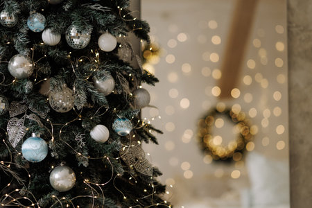 Cozy bedroom with Christmas wreath and blurred decorated tree with warm lightsの写真素材