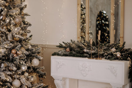 Decorated Christmas tree and festive mantel with evergreen garland in classic room with white wallの写真素材
