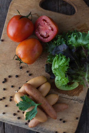 Sausages on board on wooden backgroundの写真素材