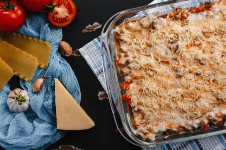 Raw lasagna ingredients and pasta products background with copy space. Top view and background of vegetables on a dark backgroundの写真素材