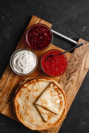 Maslenitsa Maslenitsa week is a holiday of food. Stack of Russian pancakes Pancakes with red caviar, fresh sour cream and raspberry jam. Rustic style, top viewの写真素材