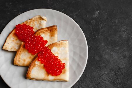 Maslenitsa Maslenitsa week is a holiday of food. Pancakes with red caviar on a plate with Cutlery. The view from the top. side view. space for textの写真素材
