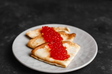 Maslenitsa Maslenitsa week is a holiday of food. Pancakes with red caviar on a plate with Cutlery. The view from the top. side view. space for textの写真素材