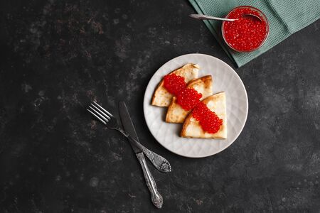 Maslenitsa Maslenitsa week is a holiday of food. Pancakes with red caviar on a plate with Cutlery. The view from the top. side view. space for textの写真素材