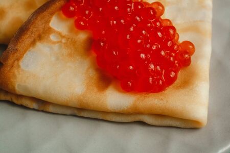 Maslenitsa Maslenitsa week is a holiday of food. Pancakes with red caviar on a plate with Cutlery. The view from the top. side view. space for textの写真素材
