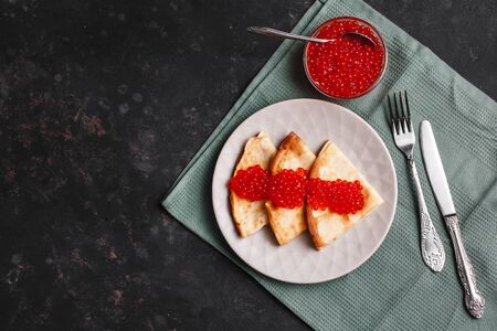 Maslenitsa Maslenitsa week is a holiday of food. Pancakes with red caviar on a plate with Cutlery. The view from the top. side view. space for textの写真素材