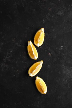 Slices of fresh lemon on a black background, top view. Fresh tropical fruit, yellow citrus, flat layer, space for textの写真素材