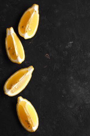 Slices of fresh lemon on a black background, top view. Fresh tropical fruit, yellow citrus, flat layer, space for textの写真素材