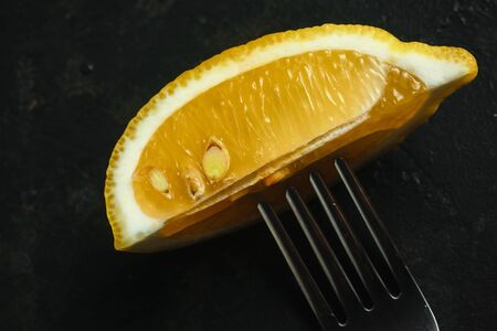 Slices of fresh lemon on a fork on a black background, top view. Fresh tropical fruit, yellow citrus, flat layer, space for textの写真素材