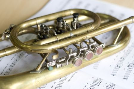 Trumpet on musical notes as background close up