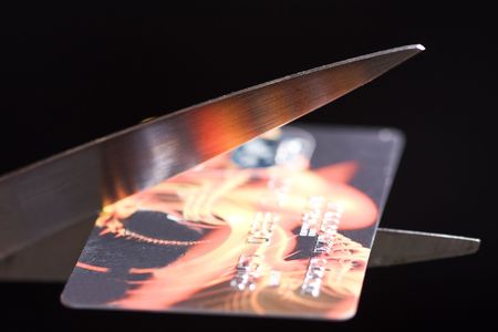 Credit card is being cut in two by scissorsの写真素材