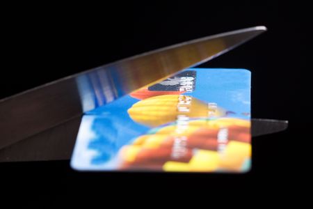 Credit card is being cut in two by scissorsの写真素材