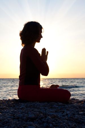 Silhouette of a woman meditating by the seaの写真素材